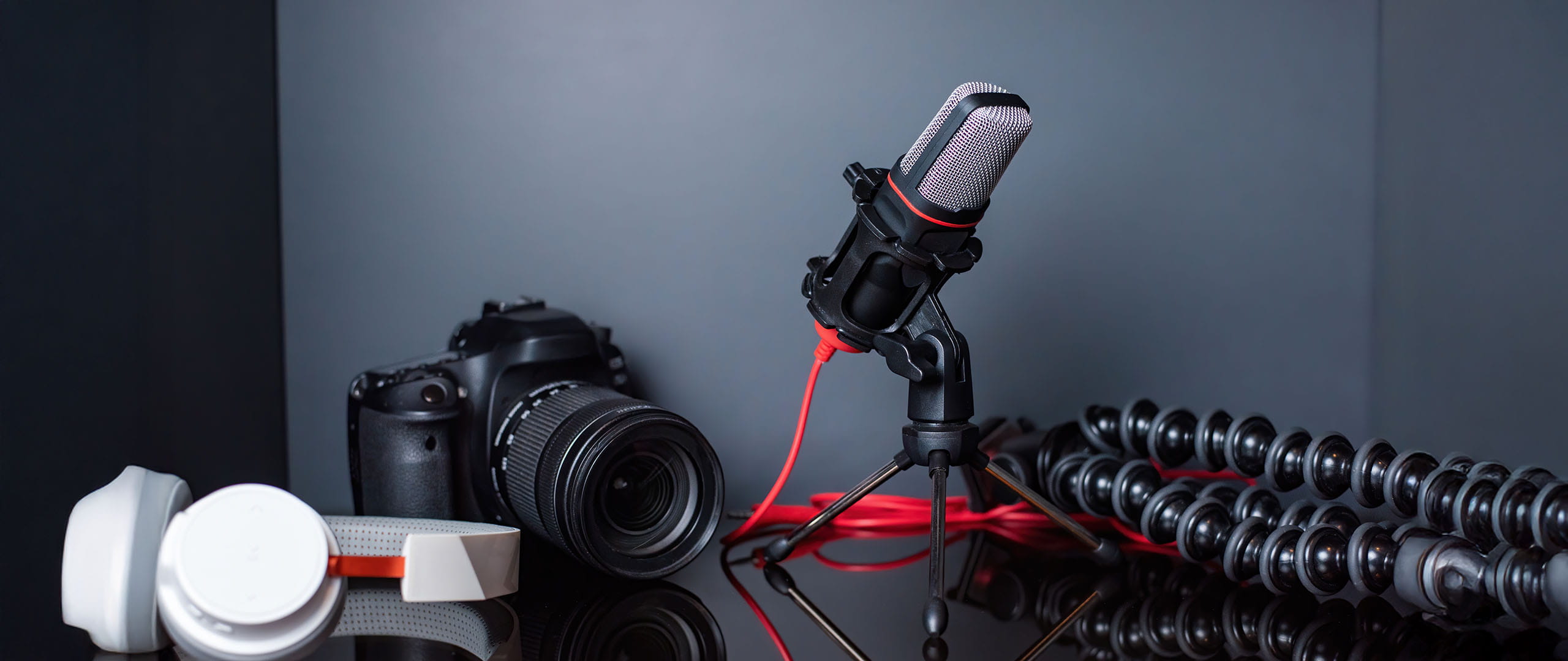 Studio setup with camera, microphone on stand, headphones, and flexible tripod arranged on a tabletop.
