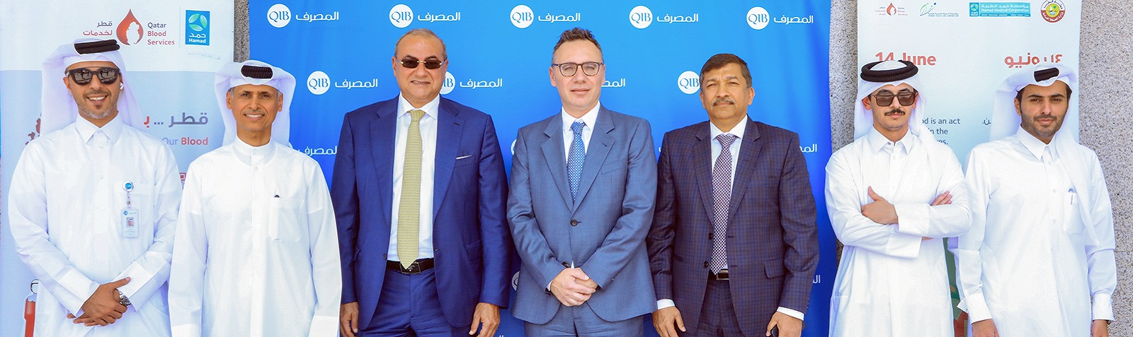 Group photo of executives standing in front of a branded backdrop at an official event.