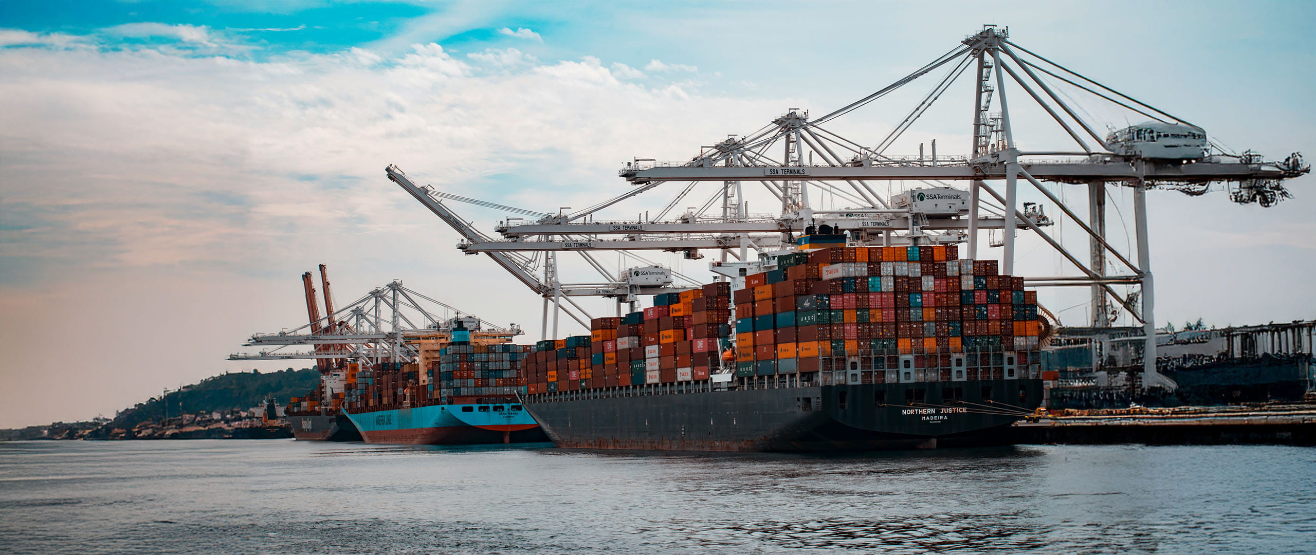 Container port scene showing cargo cranes and shipping containers.